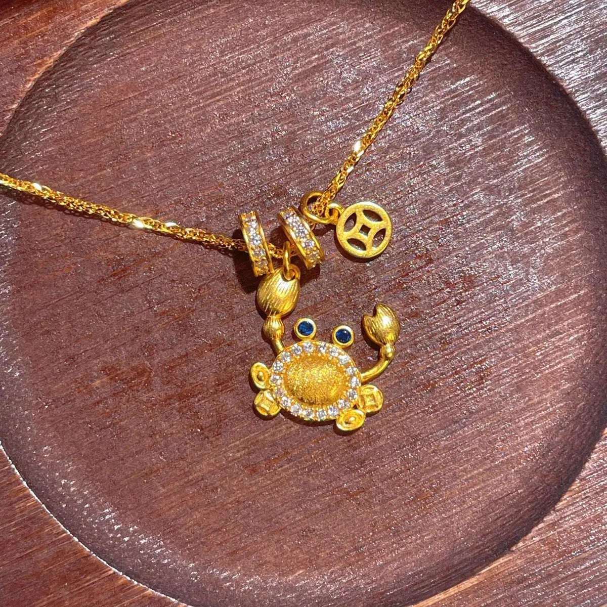 Gold-Plated Crab Pendant Necklace on wood