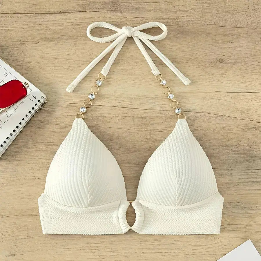 White bikini top with bow straps on a wooden surface
