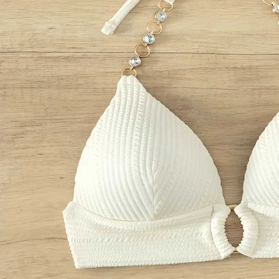 White textured bikini top with a beaded strap on a wooden surface